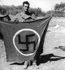 Donald S. Frederick displays a captured Nazi flag in Sicily, 1943.