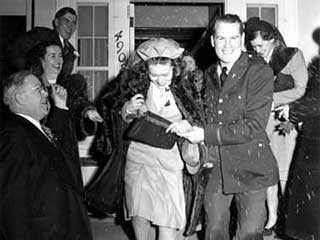 Wedding in the family of Mr. and Mrs. Harold Hall; bride and groom leaving the recption (?) surrounded by guests throwing rice, 1942. Loc. no. Collection I.366.114