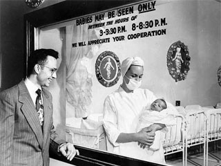 New father views child through nursery window, Abbott Hospital, 1950. Loc. no. R3.1 p18