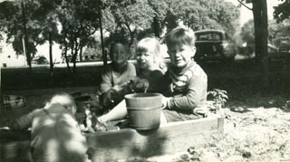 The Day children, playing with a friend in their sandbox, ca. 1949.