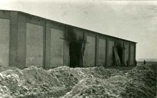 Rear of barn at Gardelegen concentration camp with mass graves in the foreground.