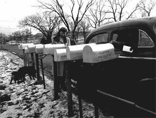 Mail carrier in an automobile placing mail in a row of mailboxes, 1945.