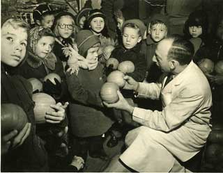 Pumpkin Joe Greenstein handing out pumpkins to school children, about 1950.