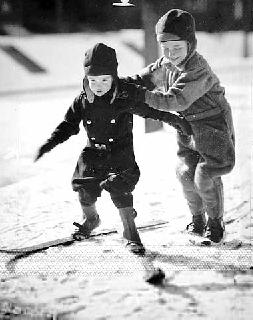 Photo: Young boy helping another young boy manipulate his skis, 1932.